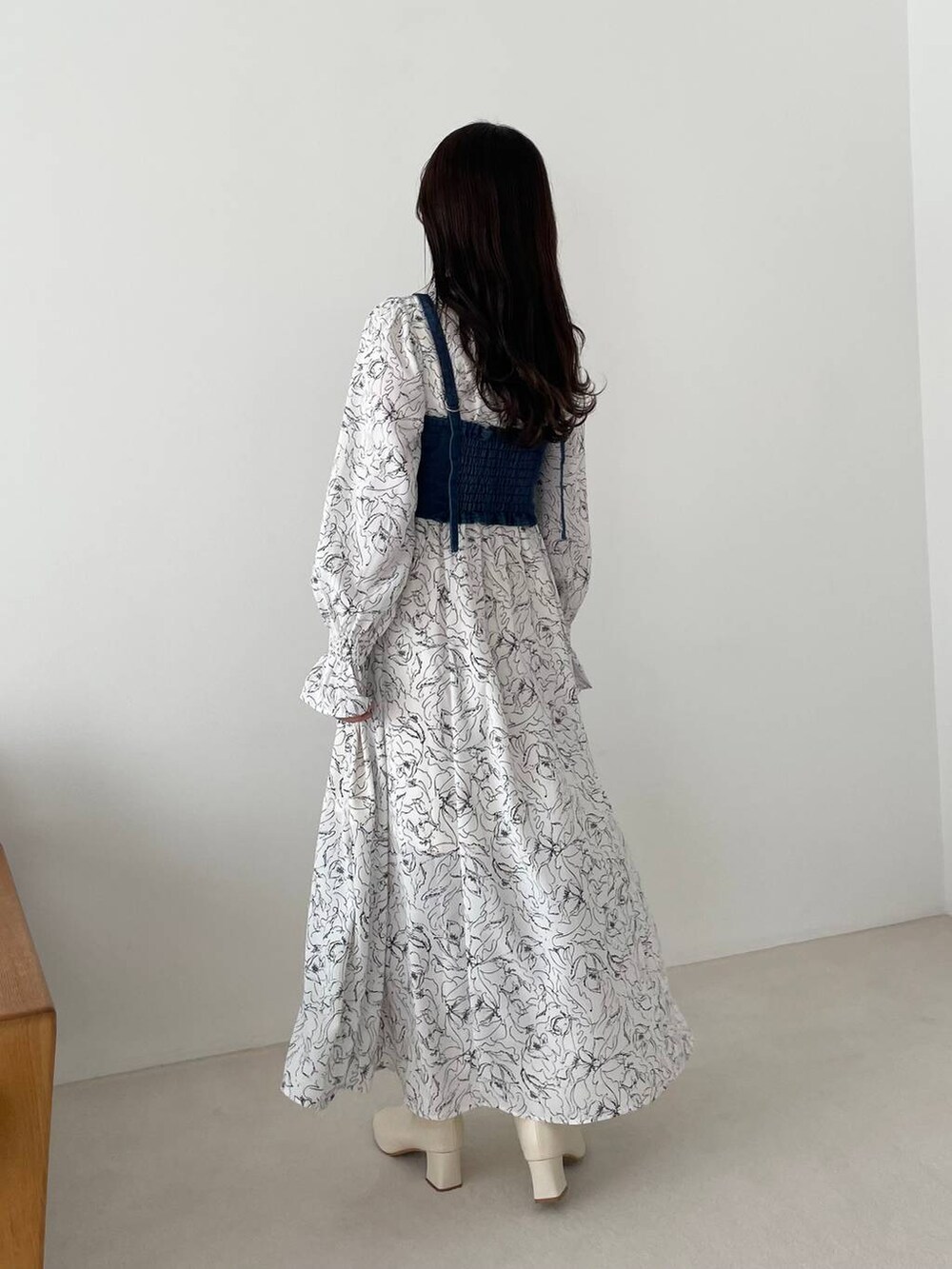 ホワイト系のブーツ、ホワイト系のワンピース、ブルー系のアンサンブルを着用したレディースの春コーディネートの2枚目の写真