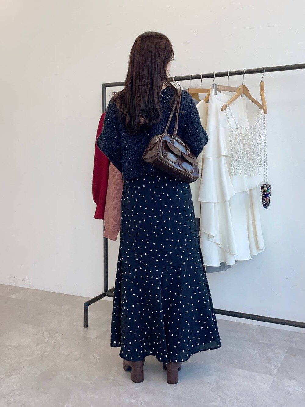 ブラウン系のブーツ、ブラウン系のハンドバッグ、ブラック系のスカートを着用したレディースの冬コーディネートの2枚目の写真