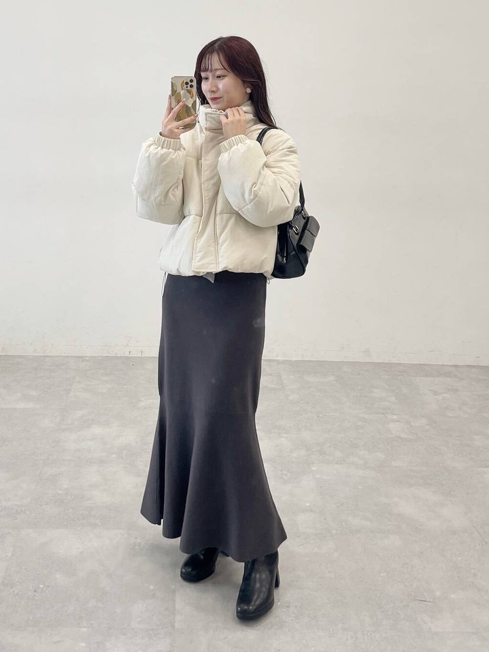 ホワイト系のブルゾン、ブラック系のブーツ、グレー系のワンピースを着用したレディースの秋コーディネートの4枚目の写真