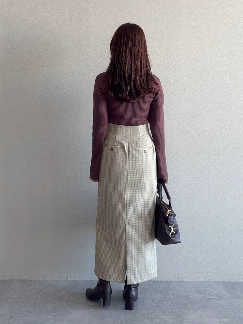 ブラウン系のボストンバッグ、ブラウン系のニット/セーター、ベージュ系のスカートを着用したレディースの冬コーディネートの2枚目の写真