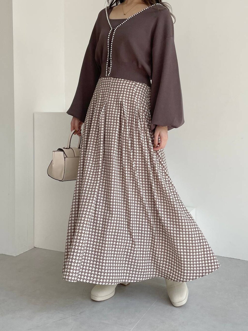 ホワイト系のハンドバッグ、ホワイト系のブーツ、ブラウン系のスカートを着用したレディースの夏コーディネートの4枚目の写真