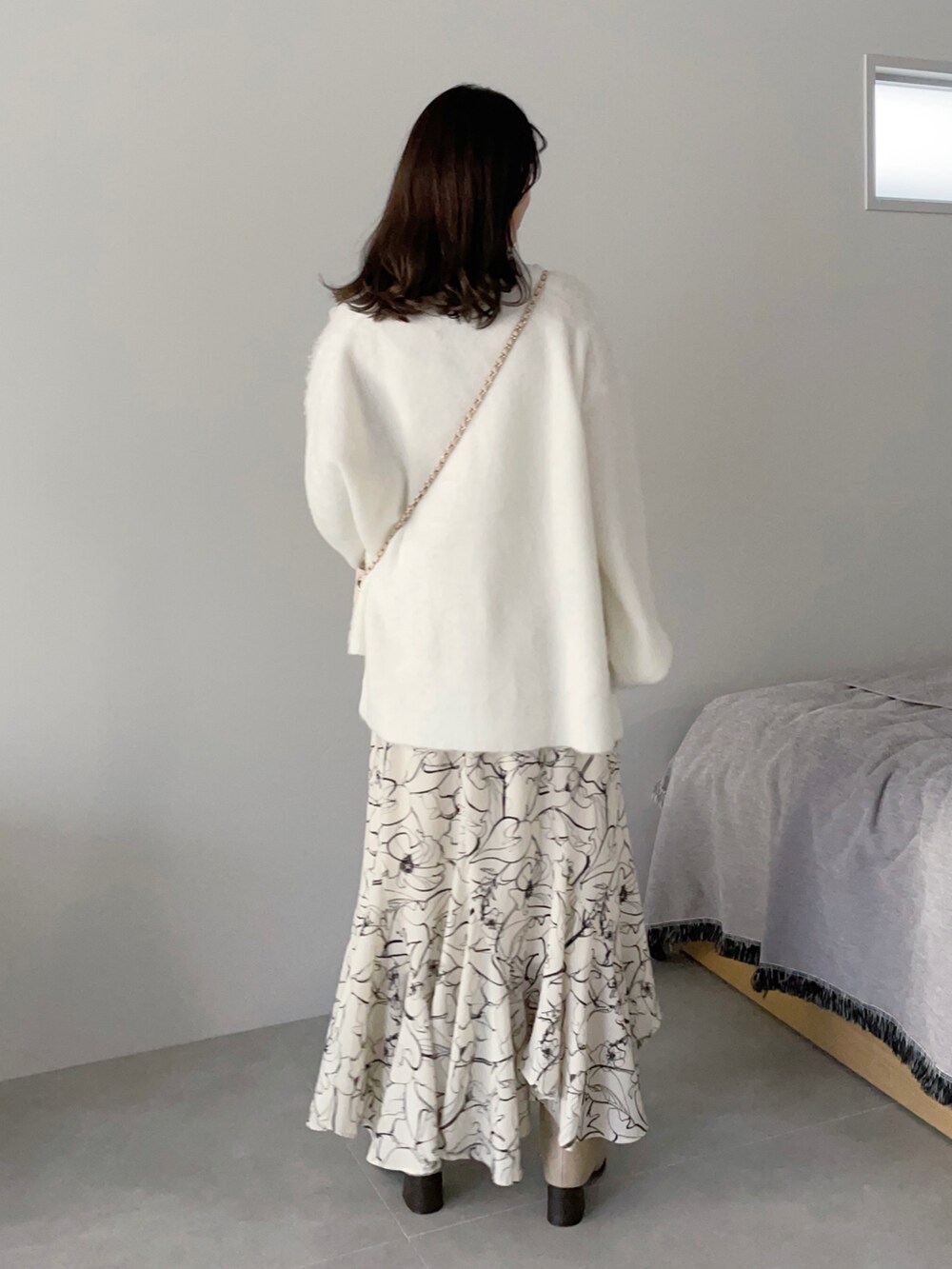 ホワイト系のニット/セーター、ホワイト系のショルダーバッグ、ホワイト系のスカートを着用したレディースの秋コーディネートの2枚目の写真