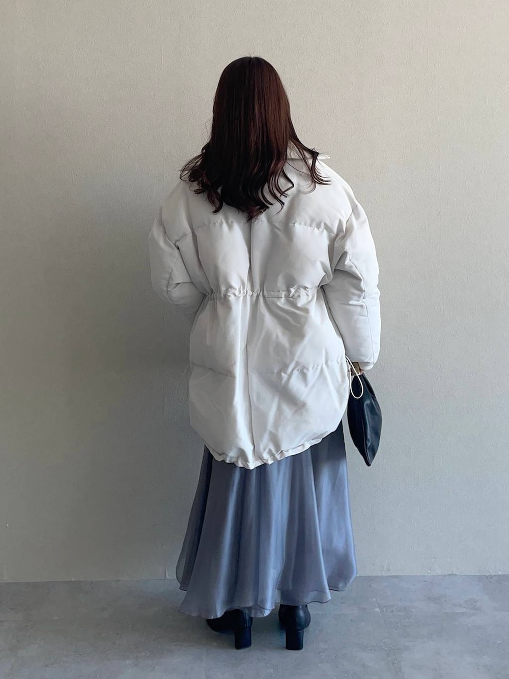 ピンク系のニット/セーター、ブラック系のハンドバッグ、ブラック系のブーツを着用したレディースの冬コーディネートの2枚目の写真