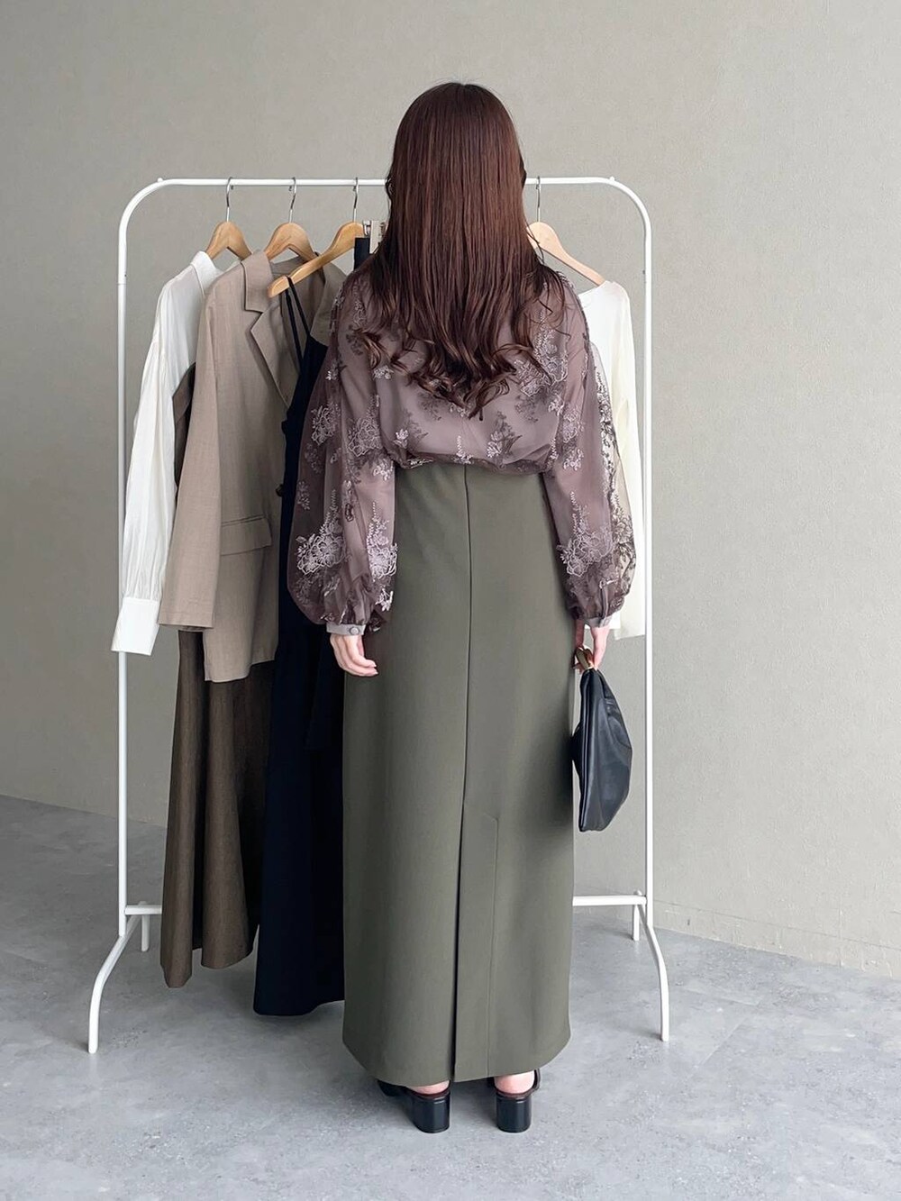 ブラック系のハンドバッグ、ブラウン系のシャツ/ブラウス、グリーン系のスカートを着用したレディースの秋コーディネートの2枚目の写真