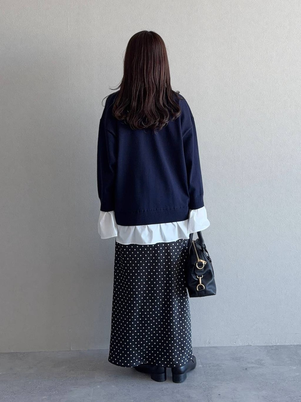 ブラック系のボストンバッグ、ブラック系のローファー、ブルー系のニット/セーターを着用したレディースの冬コーディネートの2枚目の写真