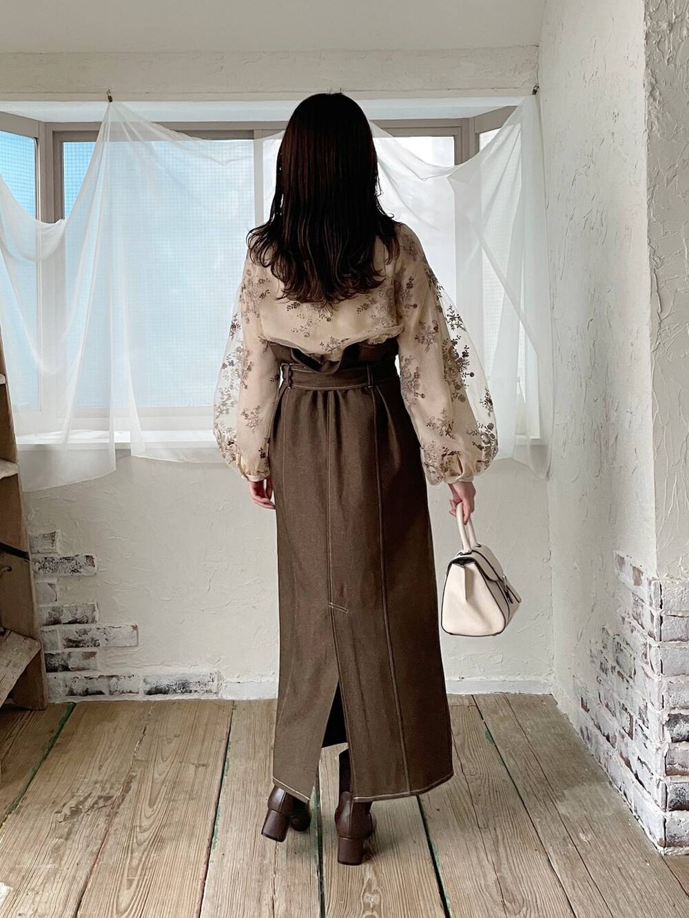 ホワイト系のハンドバッグ、ホワイト系のシャツ/ブラウス、ブラウン系のブーツを着用したレディースの冬コーディネートの2枚目の写真