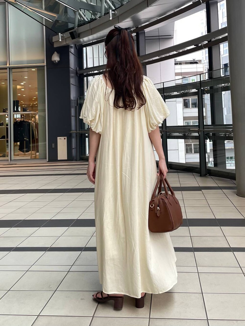 ブラウン系のサンダル、ブラウン系のショルダーバッグ、ホワイト系のワンピースを着用したレディースの夏コーディネートの2枚目の写真