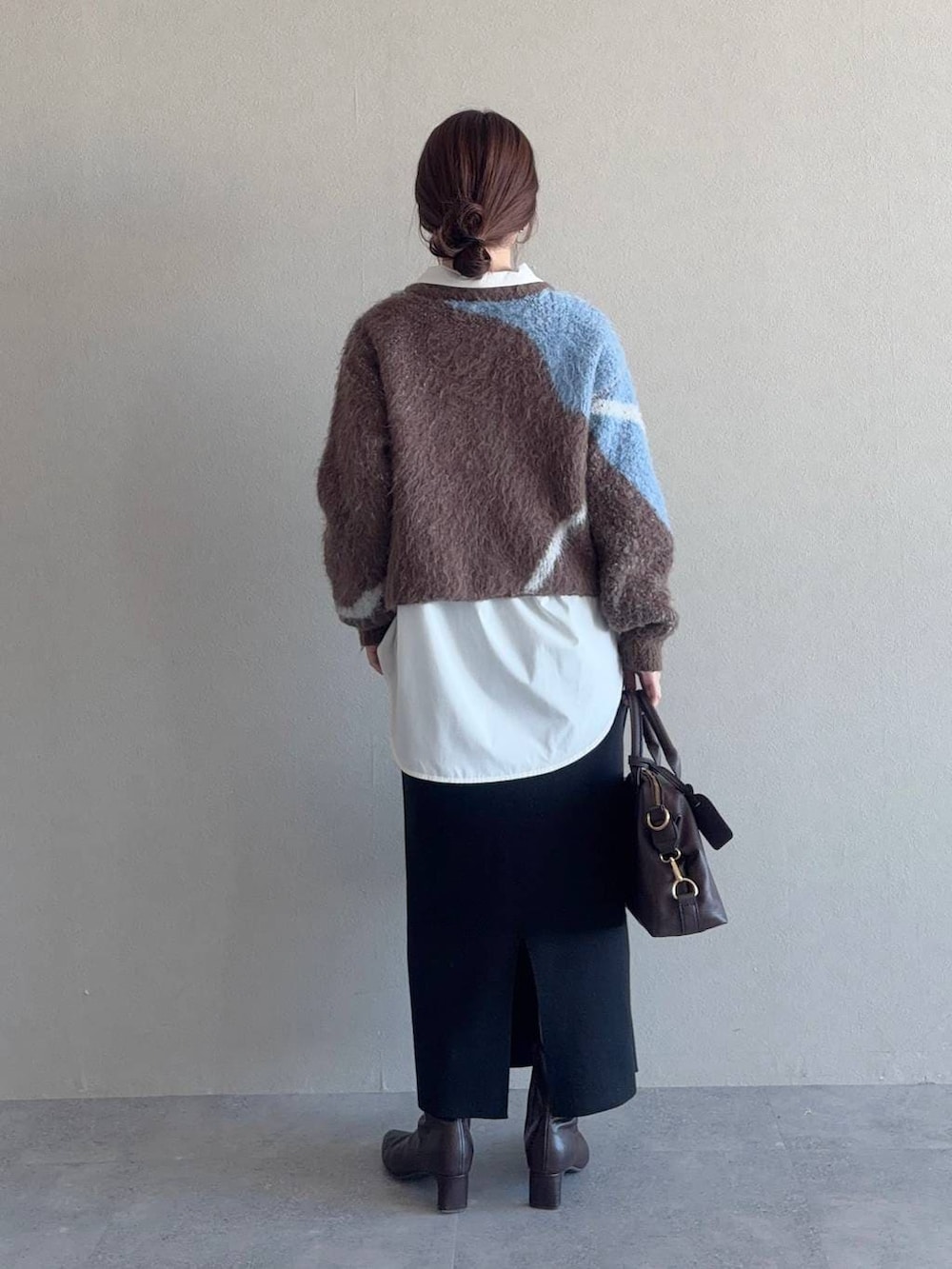 ブラウン系のニット/セーター、ブラウン系のボストンバッグ、ブラック系のスカートを着用したレディースの冬コーディネートの2枚目の写真