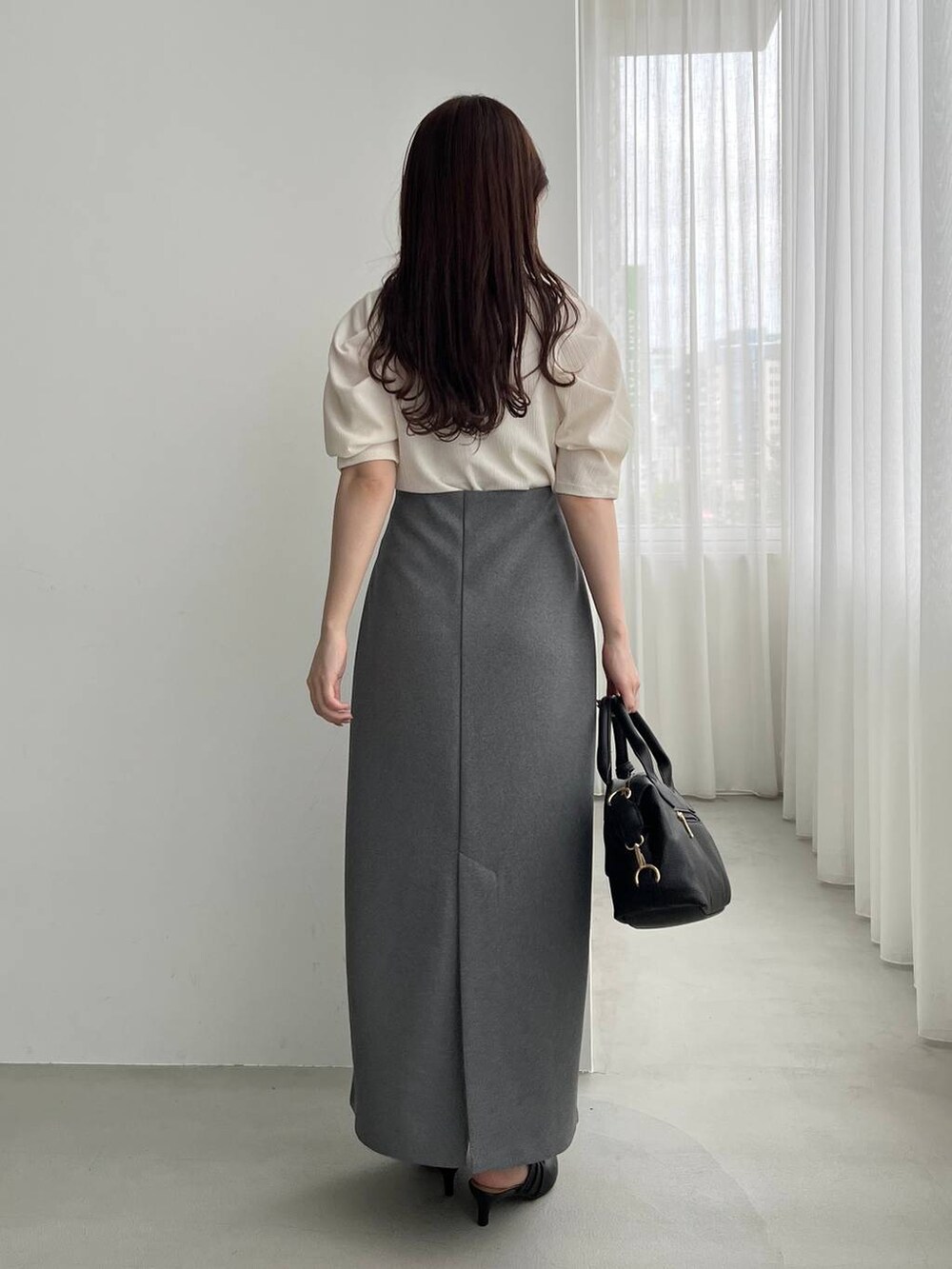 ブラック系のパンプス、ブラック系のボストンバッグ、ホワイト系のTシャツ/カットソーを着用したレディースの夏コーディネートの2枚目の写真