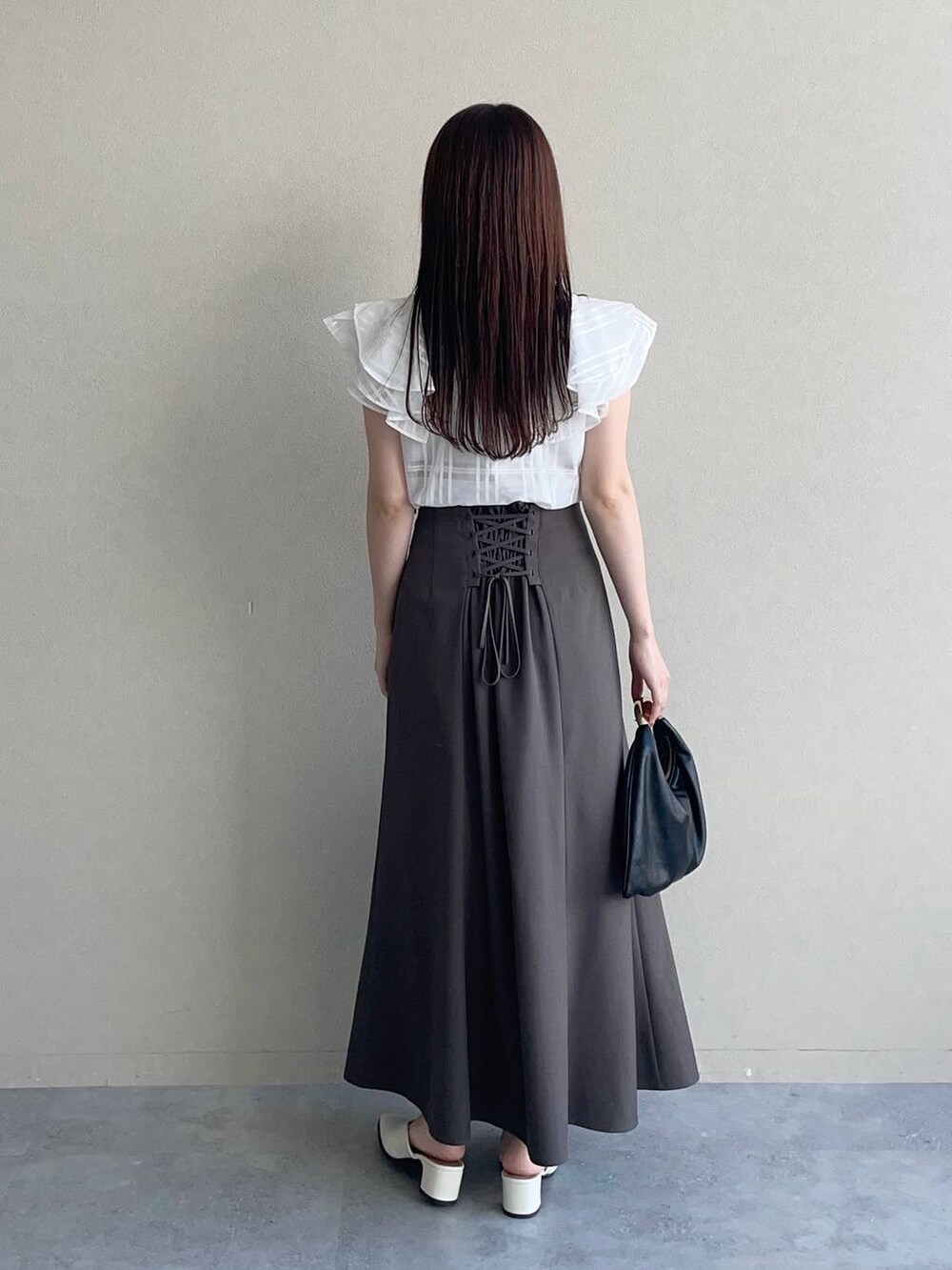 ブラック系のハンドバッグ、ホワイト系のシャツ/ブラウス、ブラウン系のスカートを着用したレディースの夏コーディネートの2枚目の写真