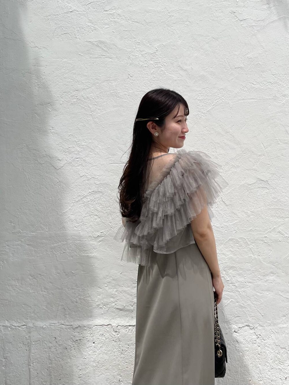 ブラック系のパンプス、グリーン系のドレス、ブラック系のショルダーバッグを着用したレディースの夏コーディネートの6枚目の写真