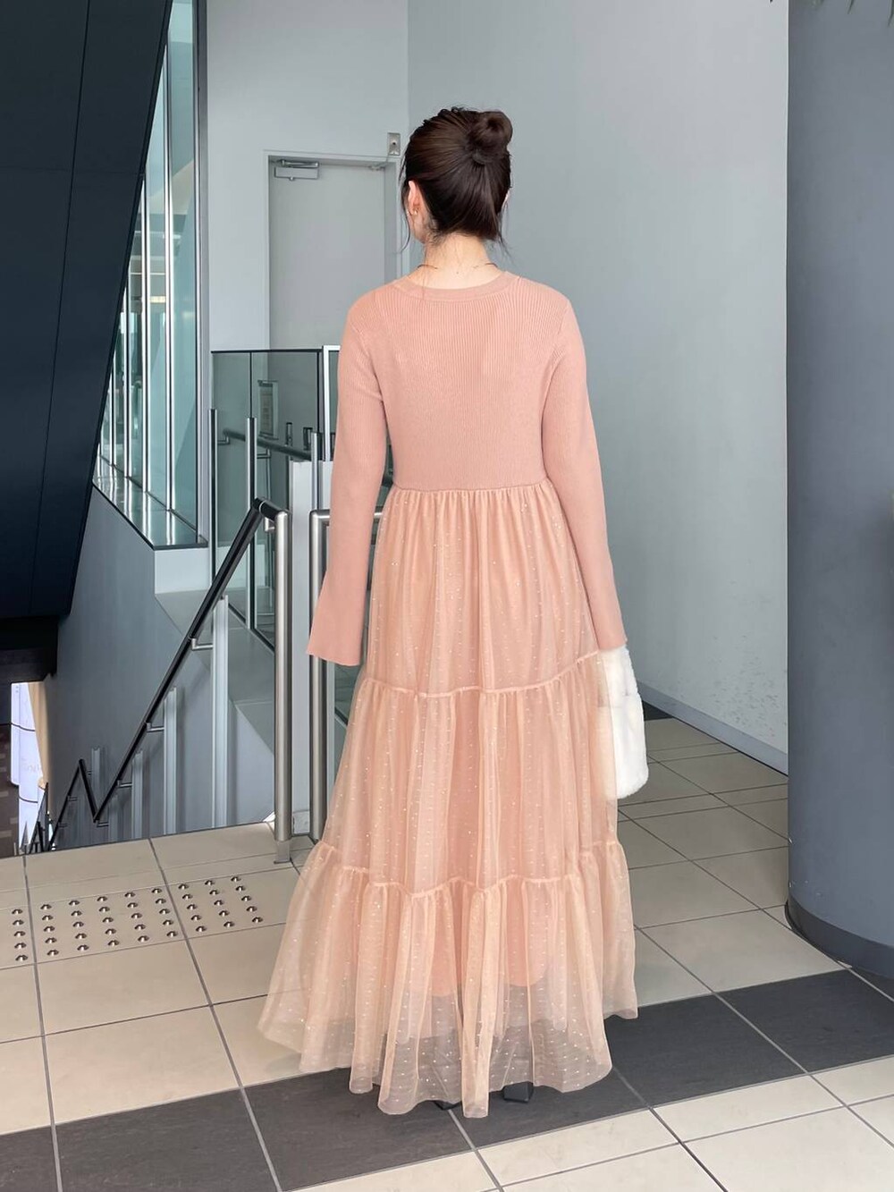 グレー系のブーツ、ホワイト系のハンドバッグ、オレンジ系のワンピースを着用したレディースの秋コーディネートの2枚目の写真