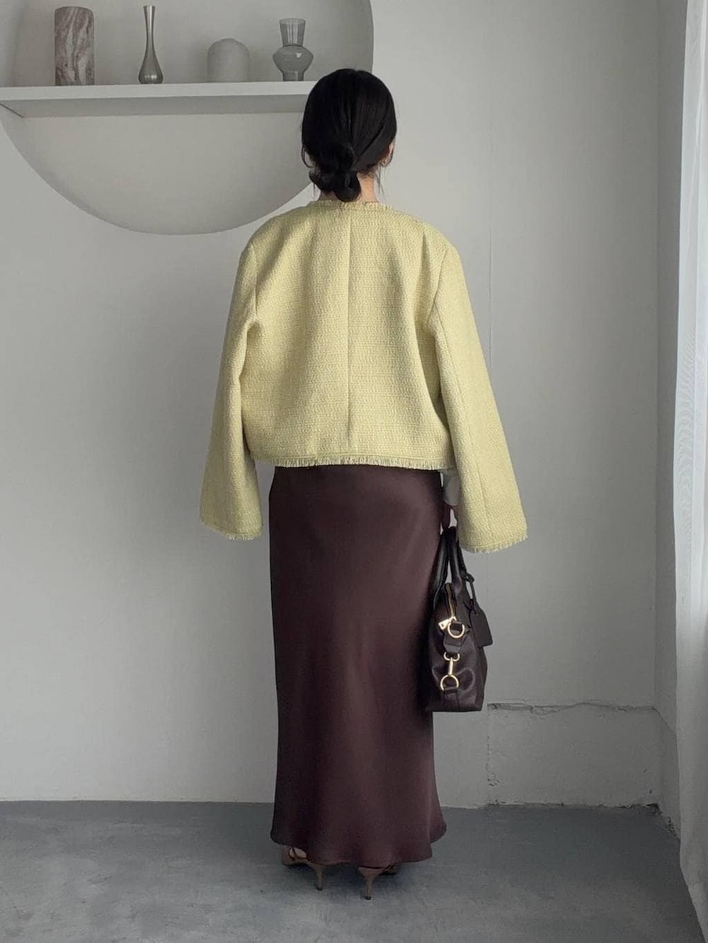 ブラウン系のボストンバッグ、ブラウン系のサンダル、イエロー系のノーカラージャケットを着用したレディースの春コーディネートの2枚目の写真