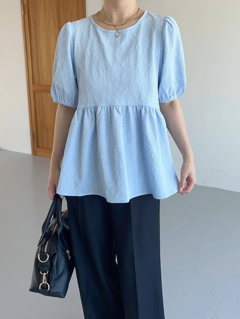 ブラック系のスラックス、ブラック系のパンプス、ブラック系のボストンバッグを着用したレディースの夏コーディネートの3枚目の写真