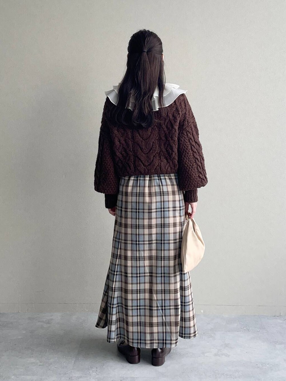 ベージュ系のハンドバッグ、ベージュ系のワンピースを着用したレディースの秋コーディネートの3枚目の写真