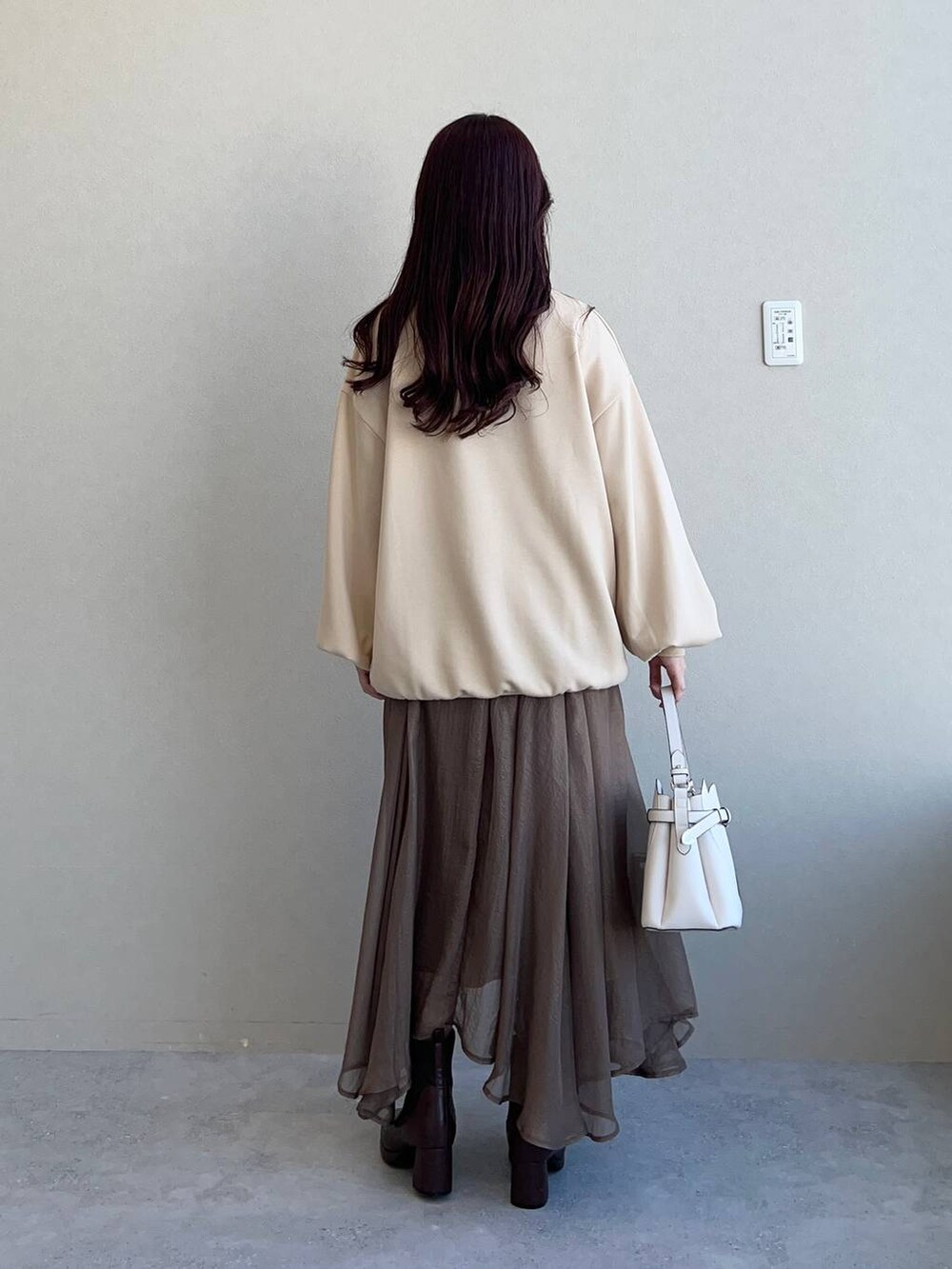 ホワイト系のショルダーバッグ、ブラウン系のブーツ、ベージュ系のスウェットを着用したレディースの冬コーディネートの2枚目の写真