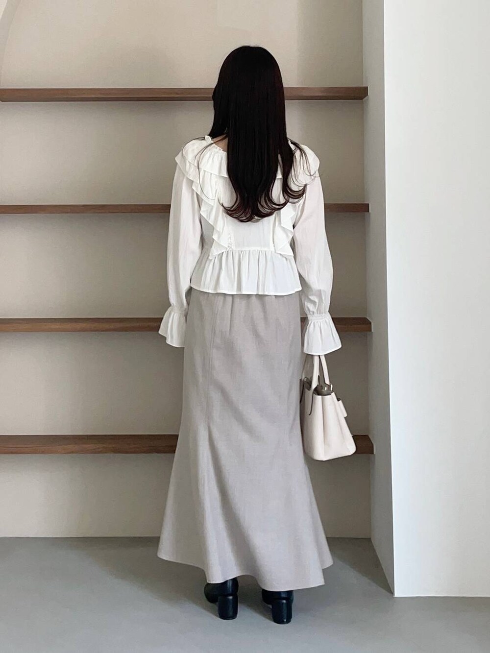 ホワイト系のショルダーバッグ、ホワイト系のシャツ/ブラウス、ブラック系のパンプスを着用したレディースの冬コーディネートの2枚目の写真