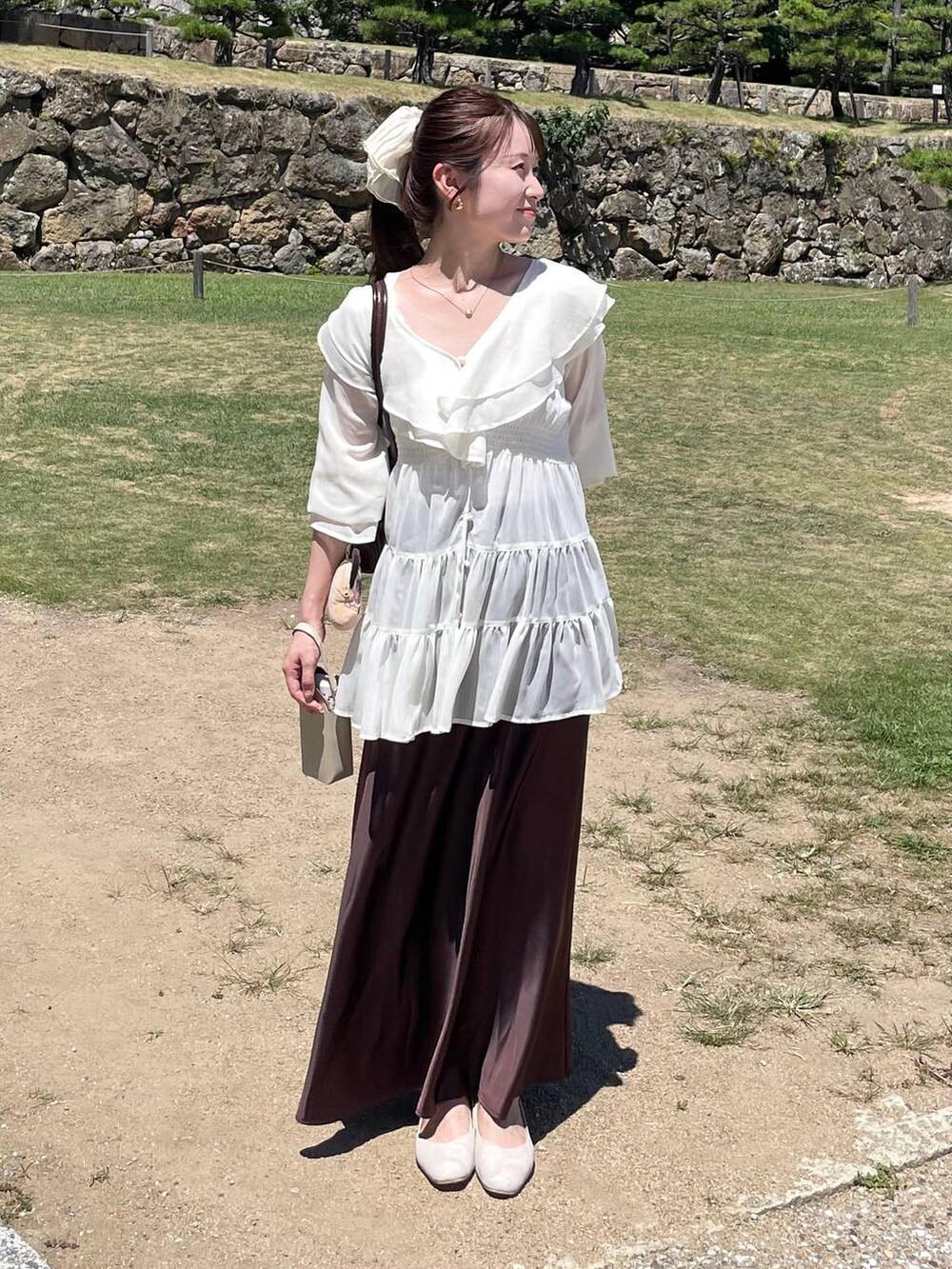 ブラウン系のスカート、ホワイト系のシャツ/ブラウス、ベージュ系のシュシュを着用したレディースの夏コーディネートの2枚目の写真