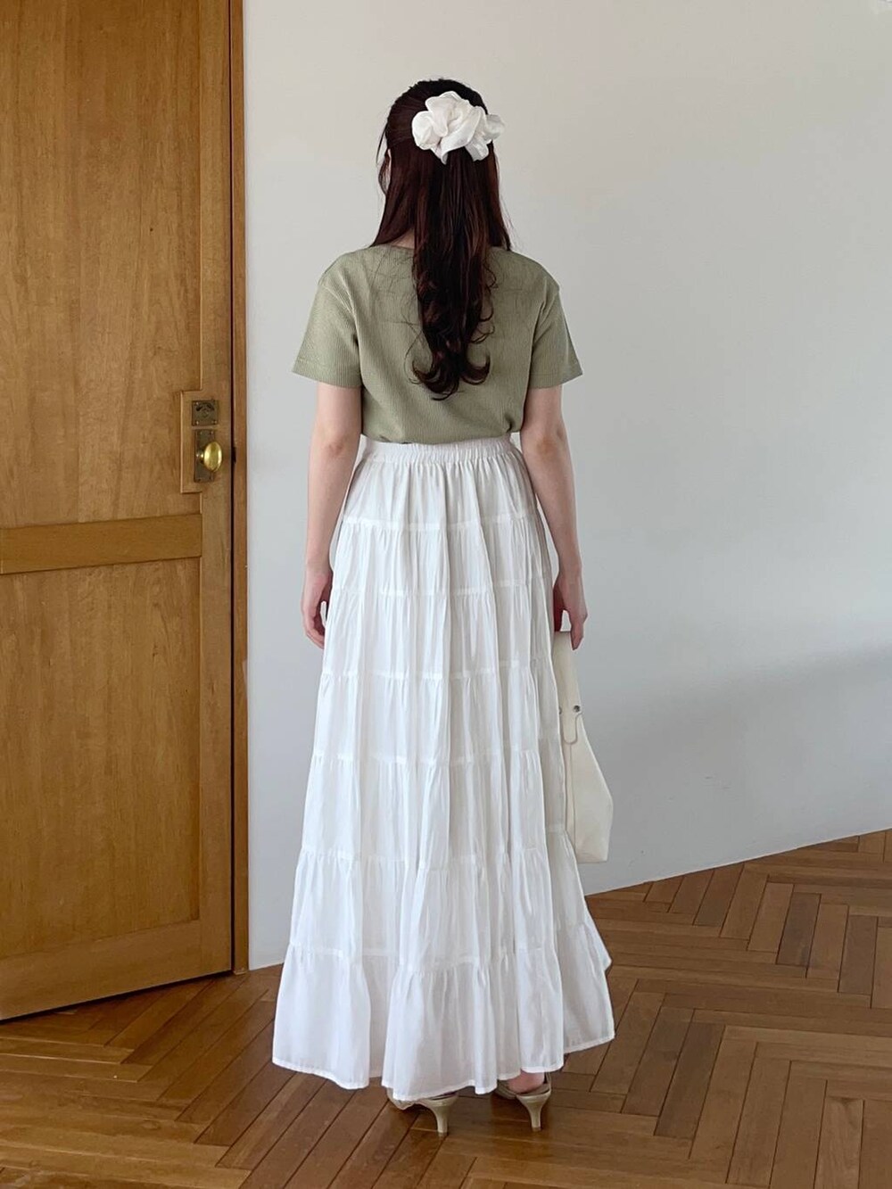 ホワイト系のショルダーバッグ、ゴールド系のパンプス、グリーン系のTシャツ/カットソーを着用したレディースの夏コーディネートの2枚目の写真