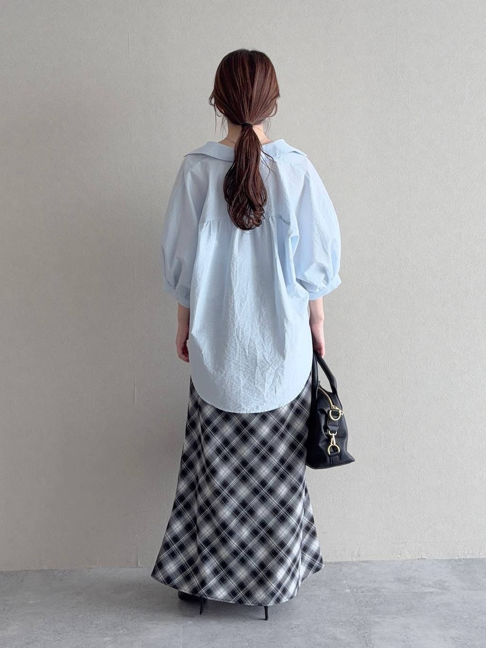ブルー系のシャツ/ブラウス、グレー系のスカート、ブラック系のボストンバッグを着用したレディースの夏コーディネートの2枚目の写真