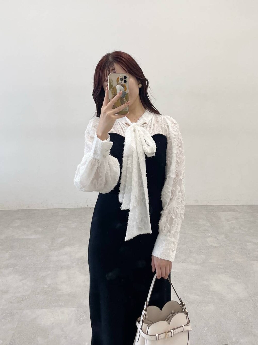 ブラック系のチェスターコート、ブラック系のワンピース、ホワイト系のショルダーバッグを着用したレディースの秋コーディネートの7枚目の写真