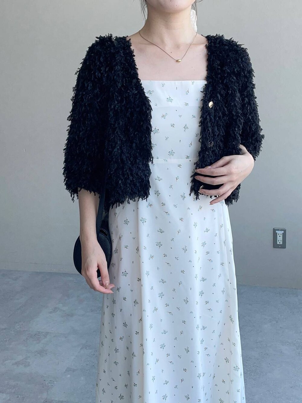 ホワイト系のワンピース、ブラック系のカーディガン/ボレロ、ブラック系のショルダーバッグを着用したレディースの夏コーディネートの3枚目の写真