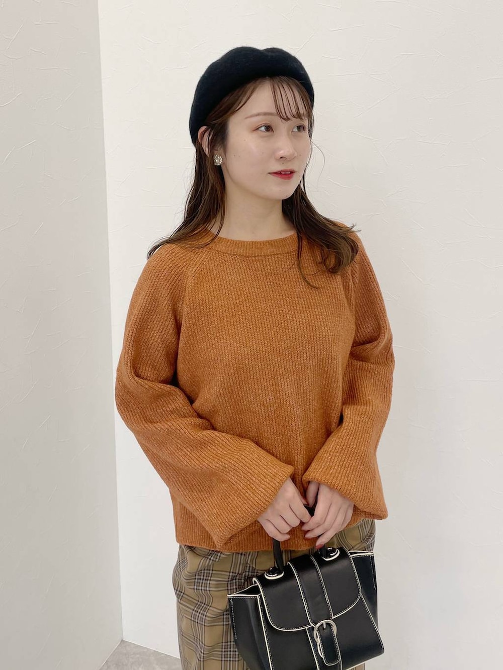 オレンジ系のニット/セーター、ブラック系のハンドバッグ、ブラック系のブーツを着用したレディースの秋コーディネートの3枚目の写真