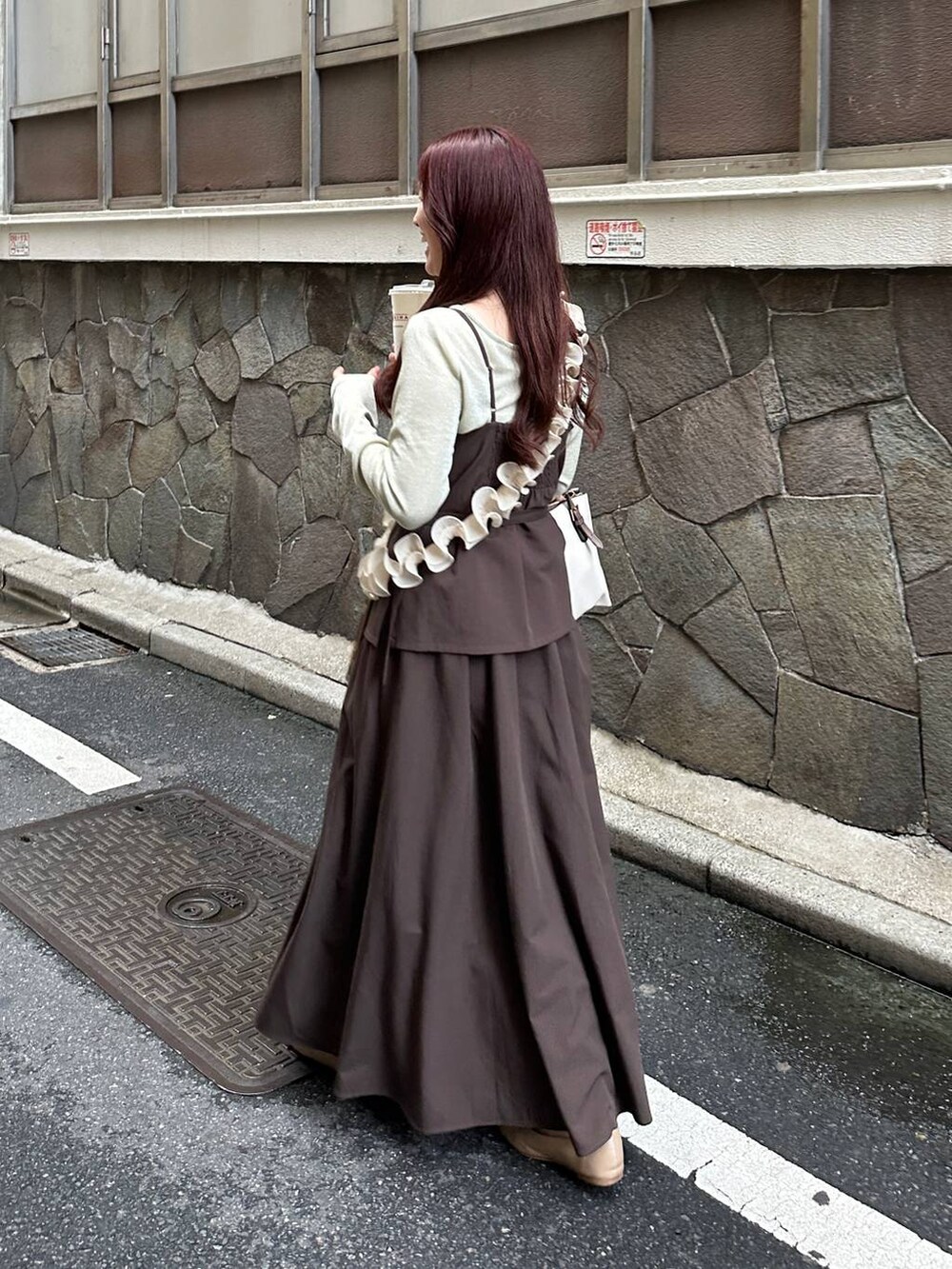 ブラウン系のワンピース、ホワイト系のTシャツ/カットソー、ホワイト系のスマホグッズを着用したレディースの冬コーディネートの2枚目の写真