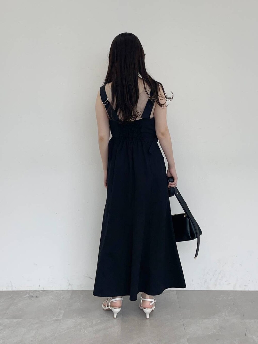 ブラック系のジャンパースカート、ブラック系のショルダーバッグ、ホワイト系のサンダルを着用したレディースの春コーディネートの2枚目の写真