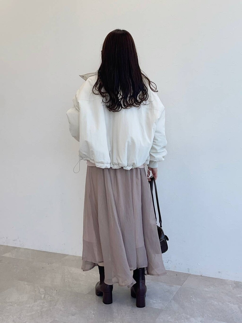 ブラウン系のブーツ、ホワイト系のブルゾン、ブラウン系のハンドバッグを着用したレディースの秋コーディネートの2枚目の写真