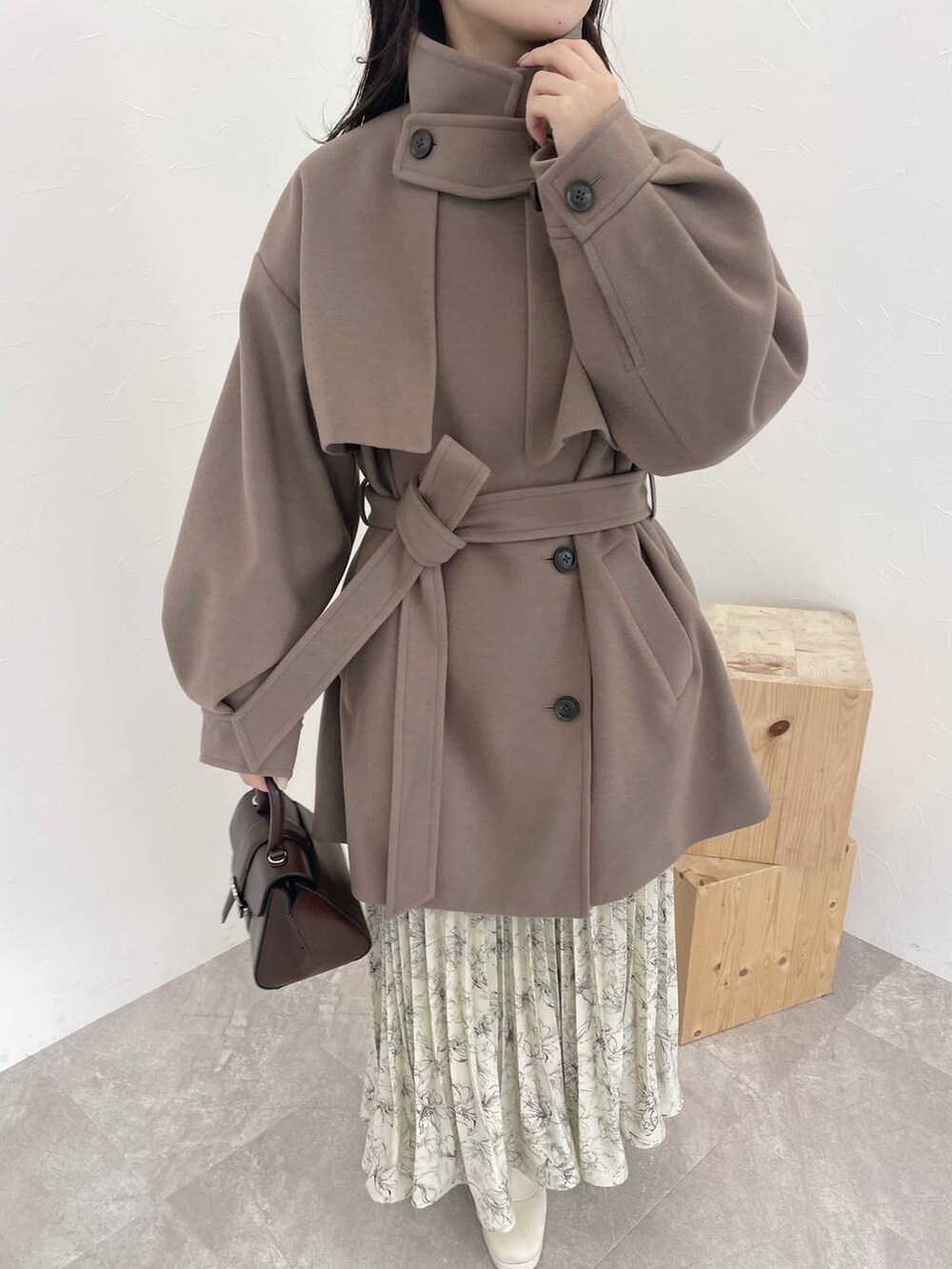 ベージュ系のニット/セーター、ブラウン系のチェスターコート、ブラウン系のハンドバッグを着用したレディースの秋コーディネートの3枚目の写真