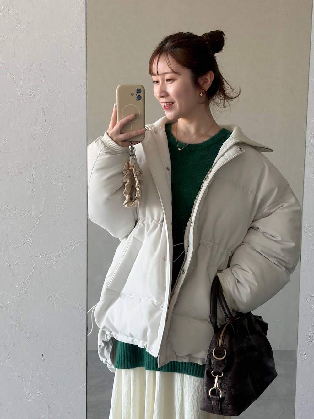 ブラウン系のボストンバッグ、ホワイト系のスカート、ブラウン系のブーツを着用したレディースの冬コーディネートの3枚目の写真