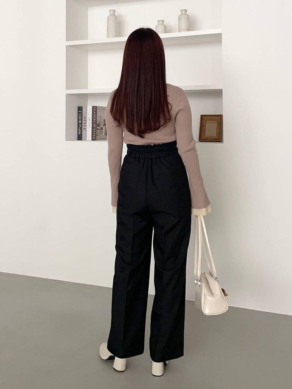 ホワイト系のブーツ、ホワイト系のハンドバッグ、ベージュ系のニット/セーターを着用したレディースの春コーディネートの2枚目の写真