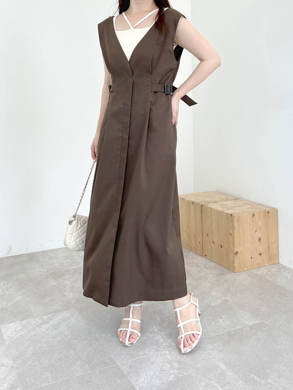 ブラウン系のジャンパースカート、ホワイト系のショルダーバッグ、ホワイト系のニット/セーターを着用したレディースの夏コーディネートの3枚目の写真