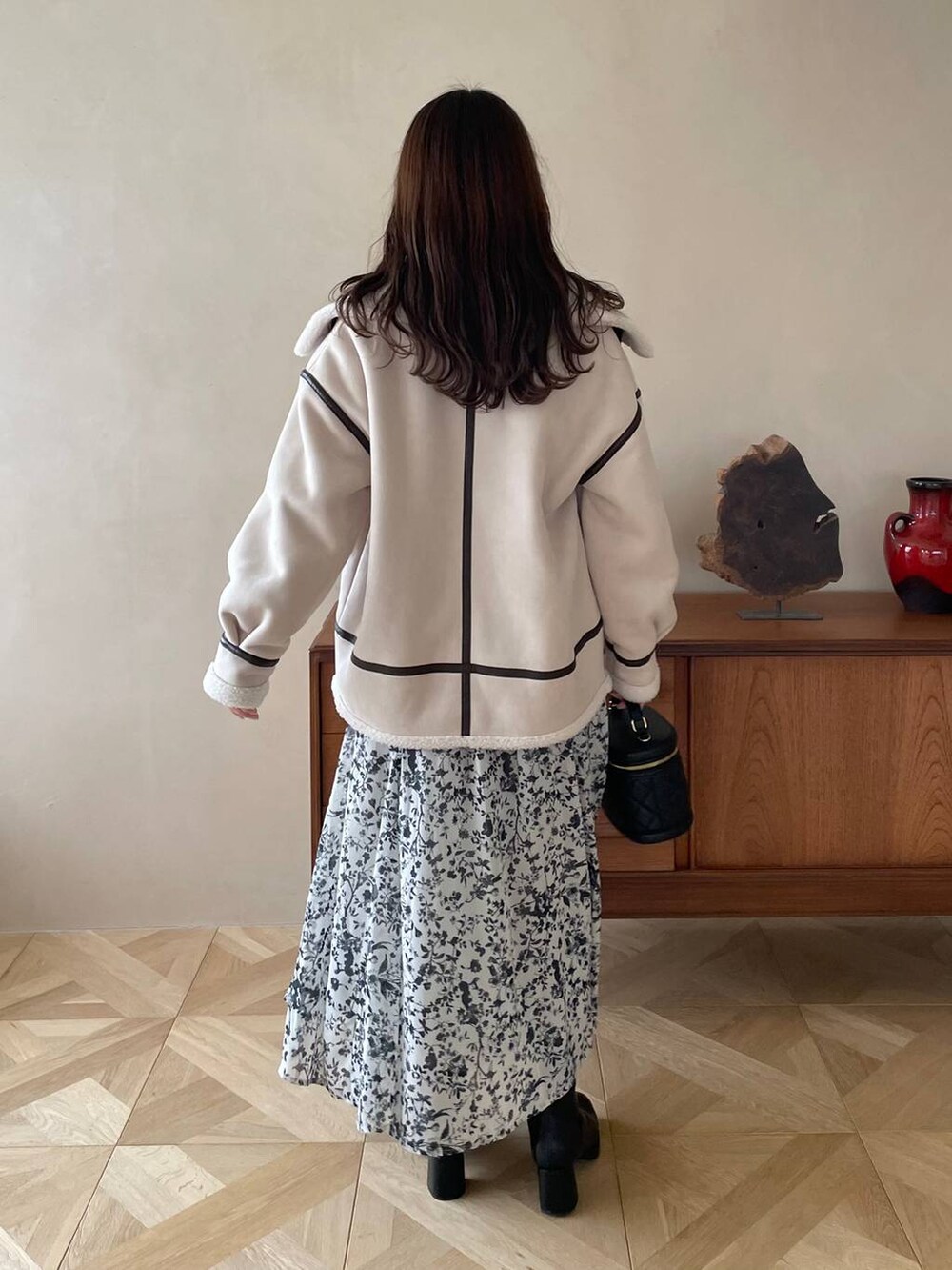 ブラック系のブーツ、ブラック系のショルダーバッグ、ホワイト系のワンピースを着用したレディースの冬コーディネートの2枚目の写真