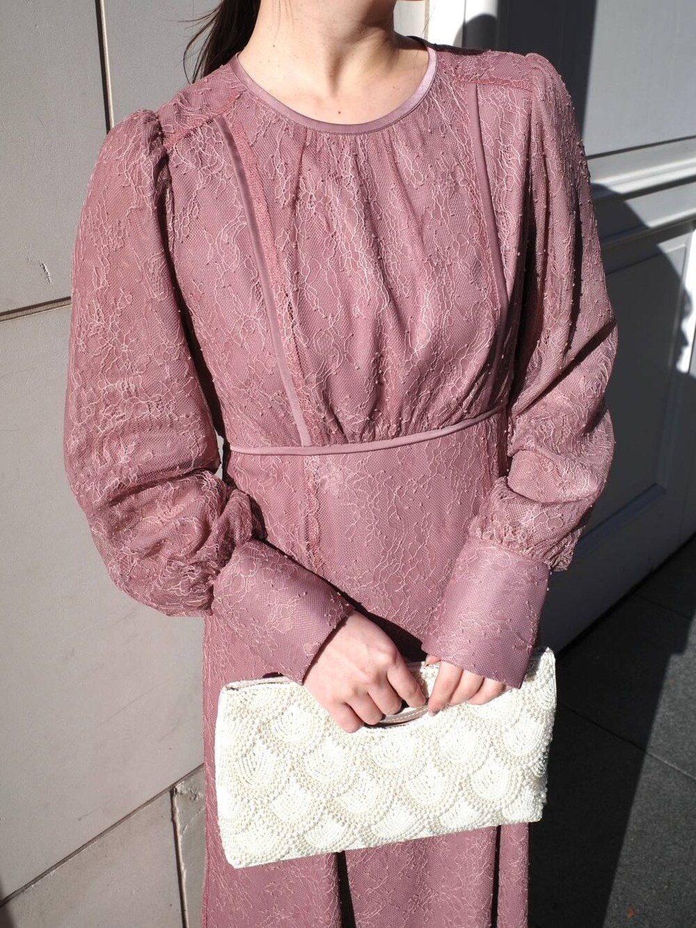 ピンク系のドレス、ベージュ系のクラッチバッグを着用したレディースの冬コーディネートの4枚目の写真