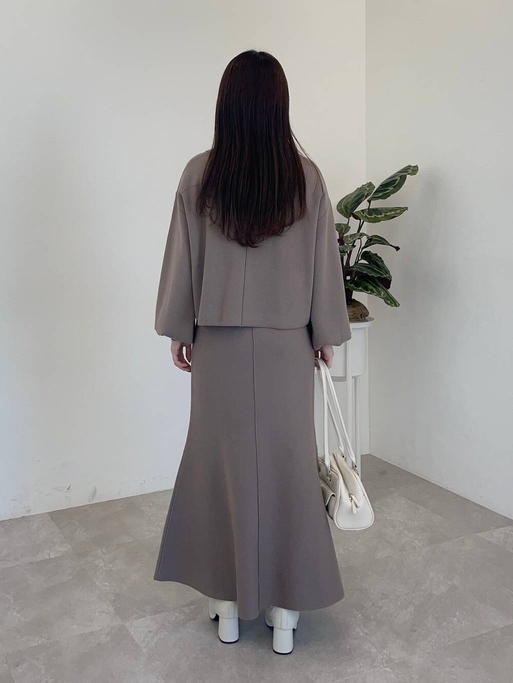 ホワイト系のチェスターコート、ホワイト系のブーツ、ホワイト系のハンドバッグを着用したレディースの冬コーディネートの4枚目の写真