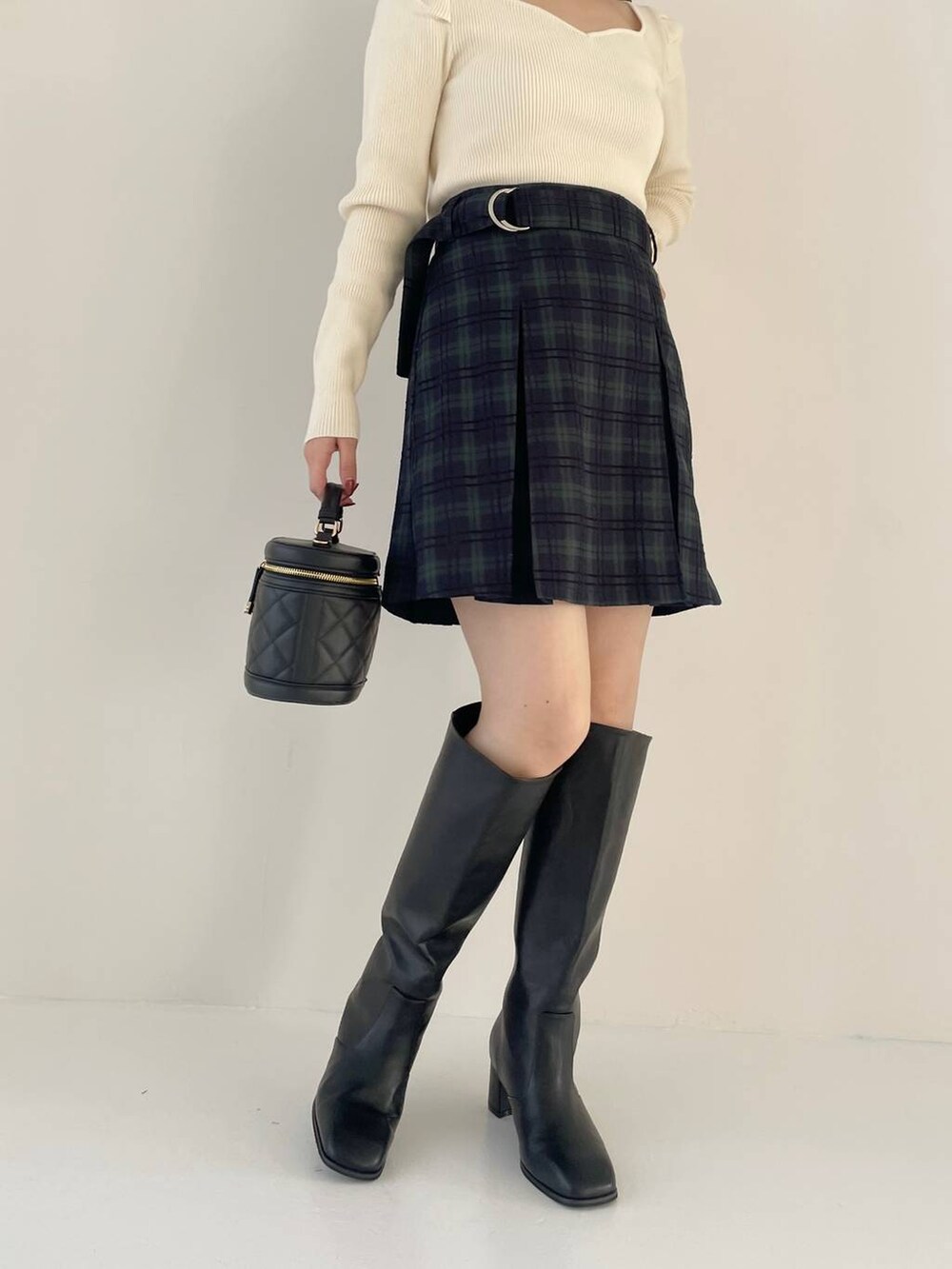 ブラック系のブーツ、ブラック系のショルダーバッグ、ホワイト系のニット/セーターを着用したレディースの秋コーディネートの5枚目の写真