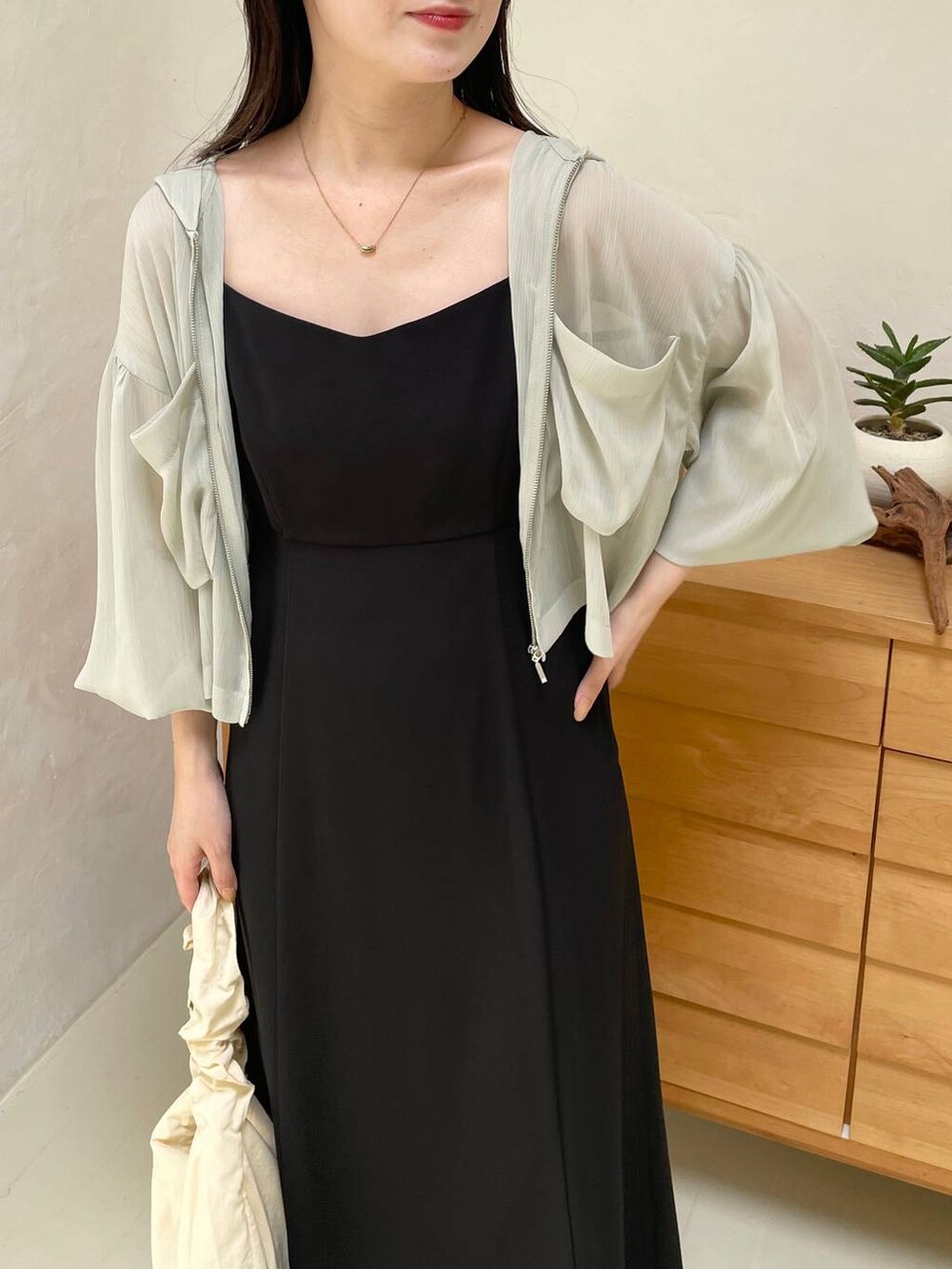 ブラック系のドレス、グリーン系のパーカー、ブラック系のサンダルを着用したレディースの夏コーディネートの3枚目の写真