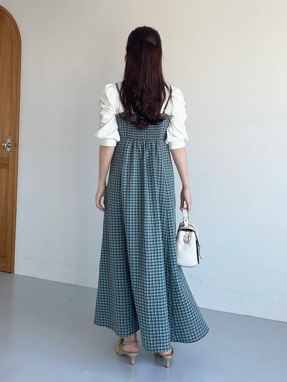 ゴールド系のパンプス、ホワイト系のショルダーバッグ、ブラウン系のワンピースを着用したレディースの夏コーディネートの2枚目の写真