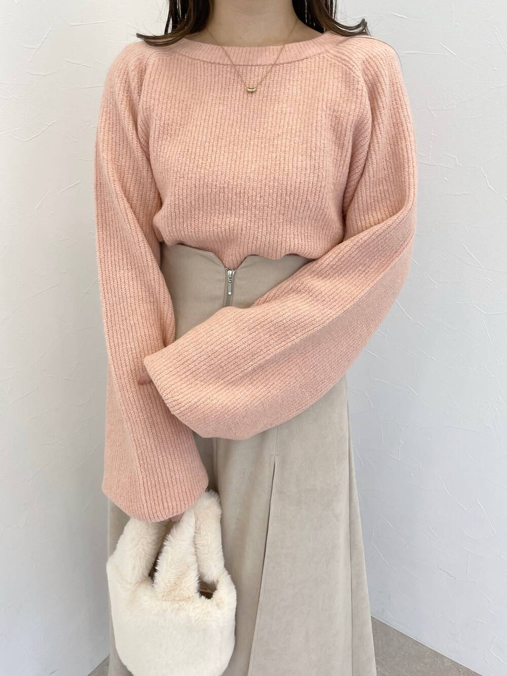 ピンク系のニット/セーター、グレー系のブーツ、ホワイト系のハンドバッグを着用したレディースの冬コーディネートの3枚目の写真