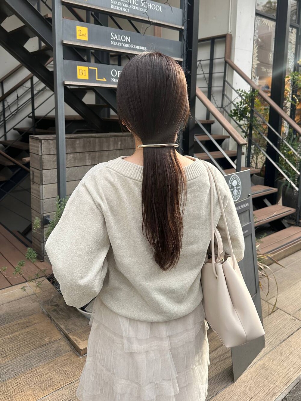 ホワイト系のスカート、ホワイト系のニット/セーター、ゴールド系のバレッタ/ヘアクリップを着用したレディースの冬コーディネートの3枚目の写真