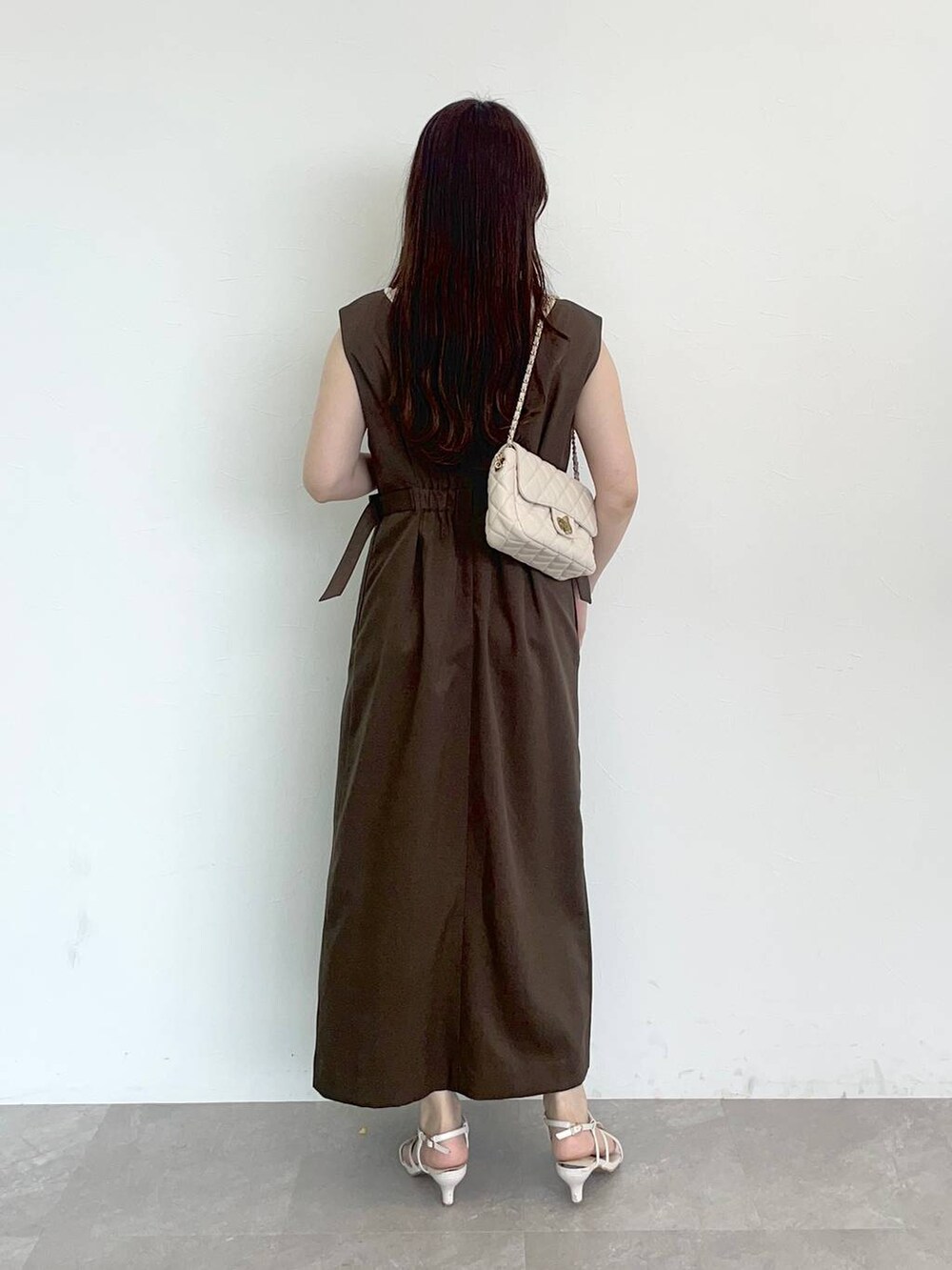 ブラウン系のジャンパースカート、ホワイト系のショルダーバッグ、ホワイト系のニット/セーターを着用したレディースの夏コーディネートの2枚目の写真