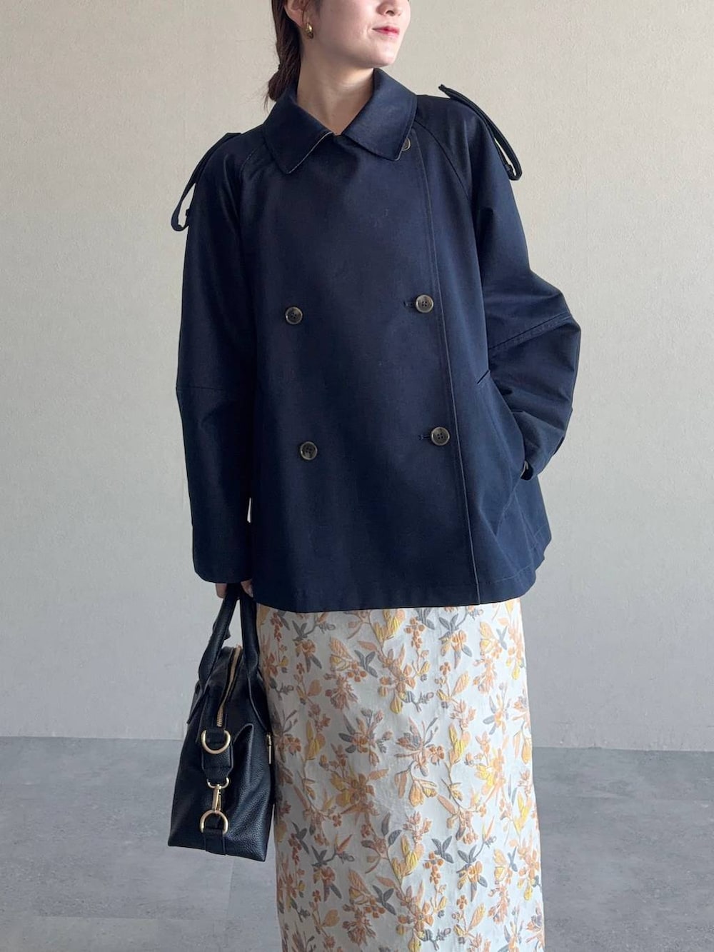 ブラック系のボストンバッグ、ホワイト系のスカート、ブラック系のパンプスを着用したレディースの冬コーディネートの3枚目の写真