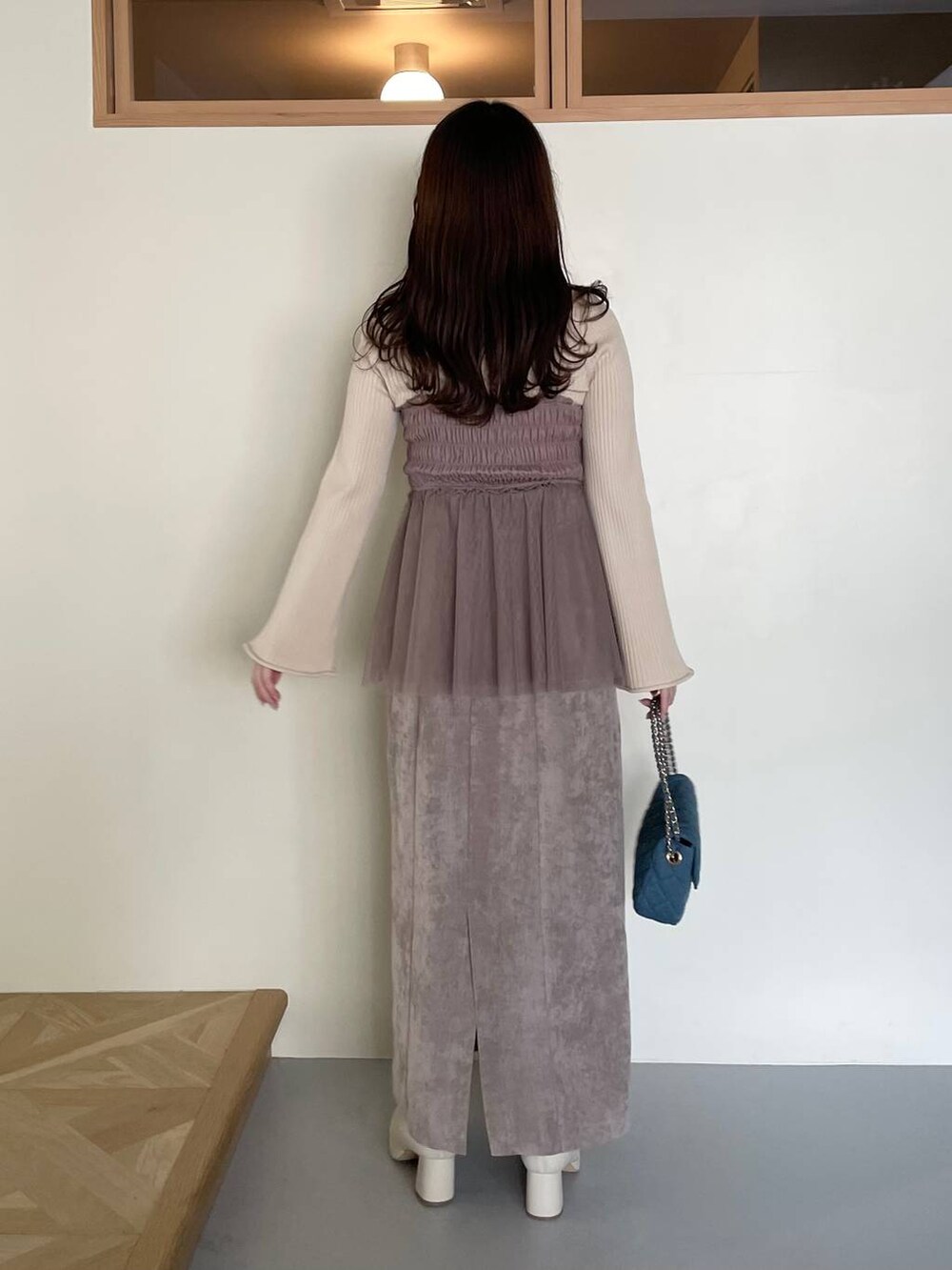 ブラウン系のスカート、ブルー系のショルダーバッグ、ホワイト系のブーツを着用したレディースの冬コーディネートの2枚目の写真