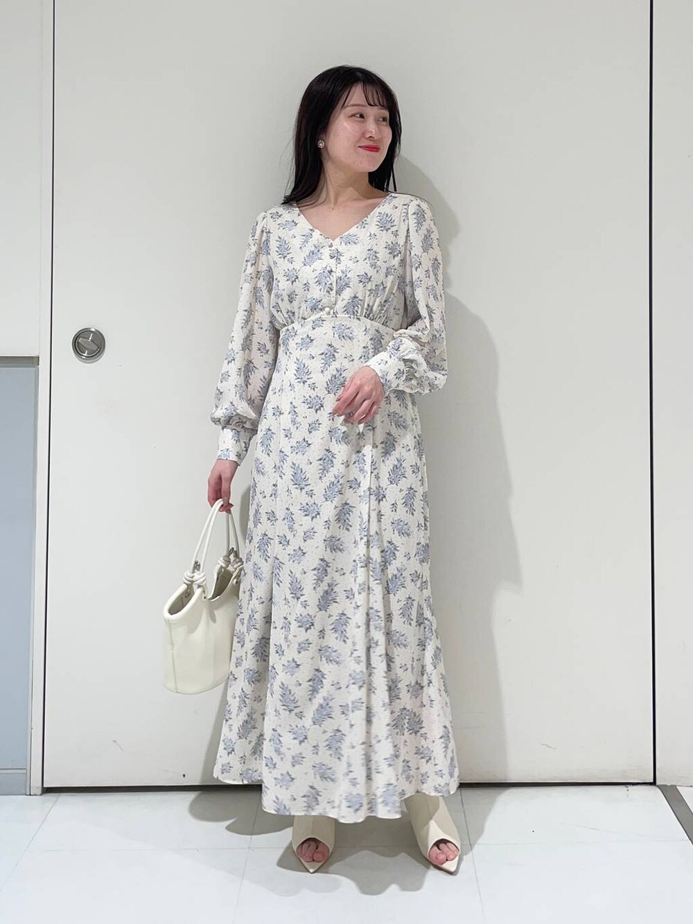 ブルー系のワンピース、ホワイト系のブーツ、グレー系のトレンチコートを着用したレディースの春コーディネートの5枚目の写真