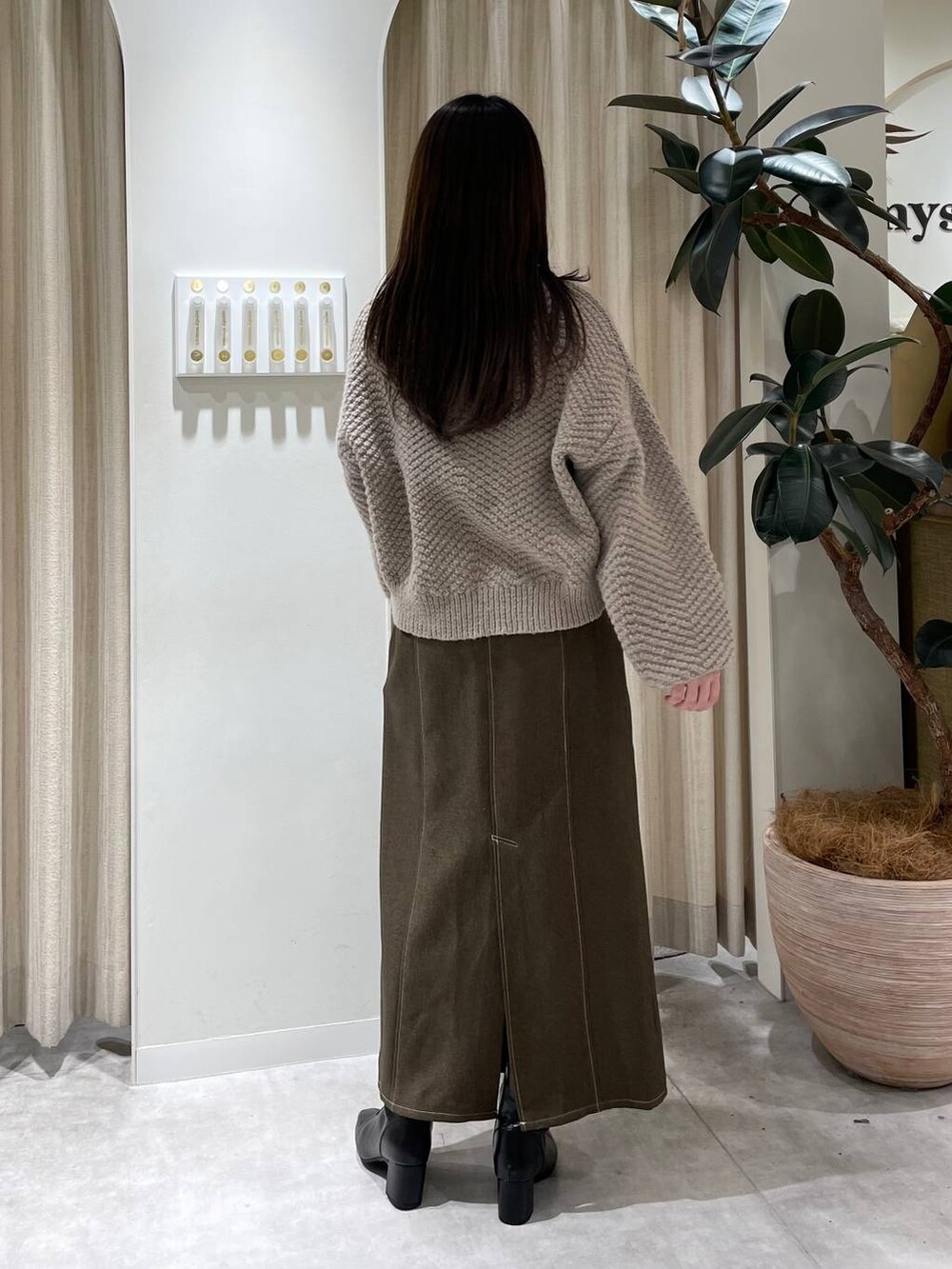 ブラック系のブーツ、ブラウン系のスカート、ベージュ系のニット/セーターを着用したレディースの冬コーディネートの2枚目の写真