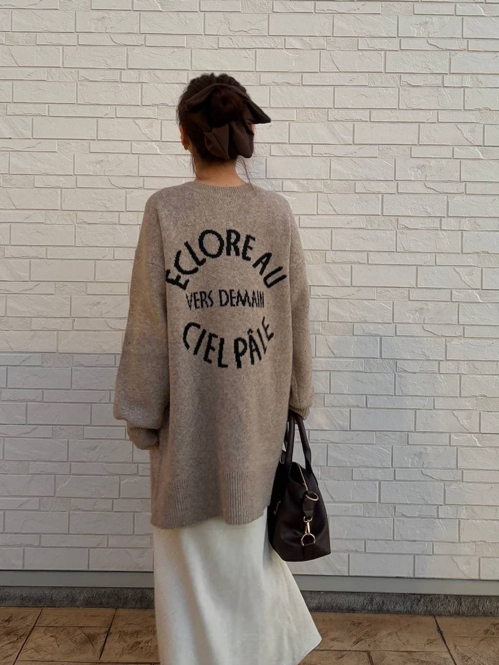 ホワイト系のスカート、ブラウン系のボストンバッグ、ベージュ系のカーディガン/ボレロを着用したレディースの冬コーディネートの3枚目の写真