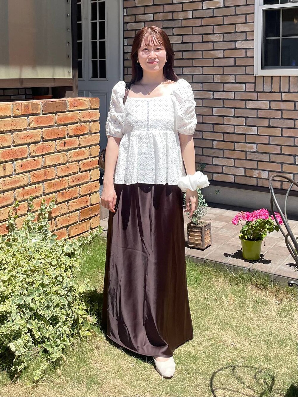 ブラウン系のスカート、ホワイト系のシャツ/ブラウスを着用したレディースの夏コーディネートの2枚目の写真