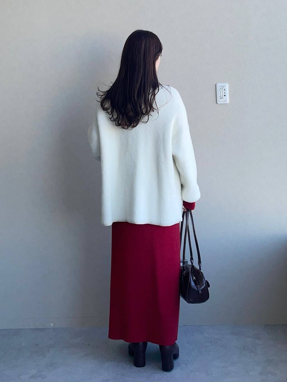 ブラック系のブーツ、ブラック系のハンドバッグ、ホワイト系のカーディガン/ボレロを着用したレディースの冬コーディネートの2枚目の写真